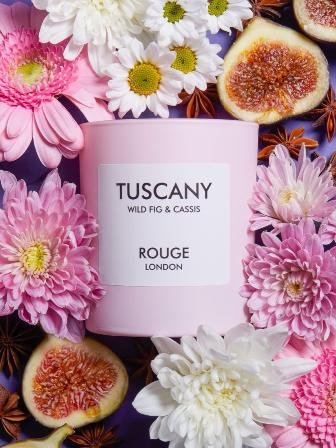 White candle containers surrounded by pink flowers and fresh figs in romantic styling.